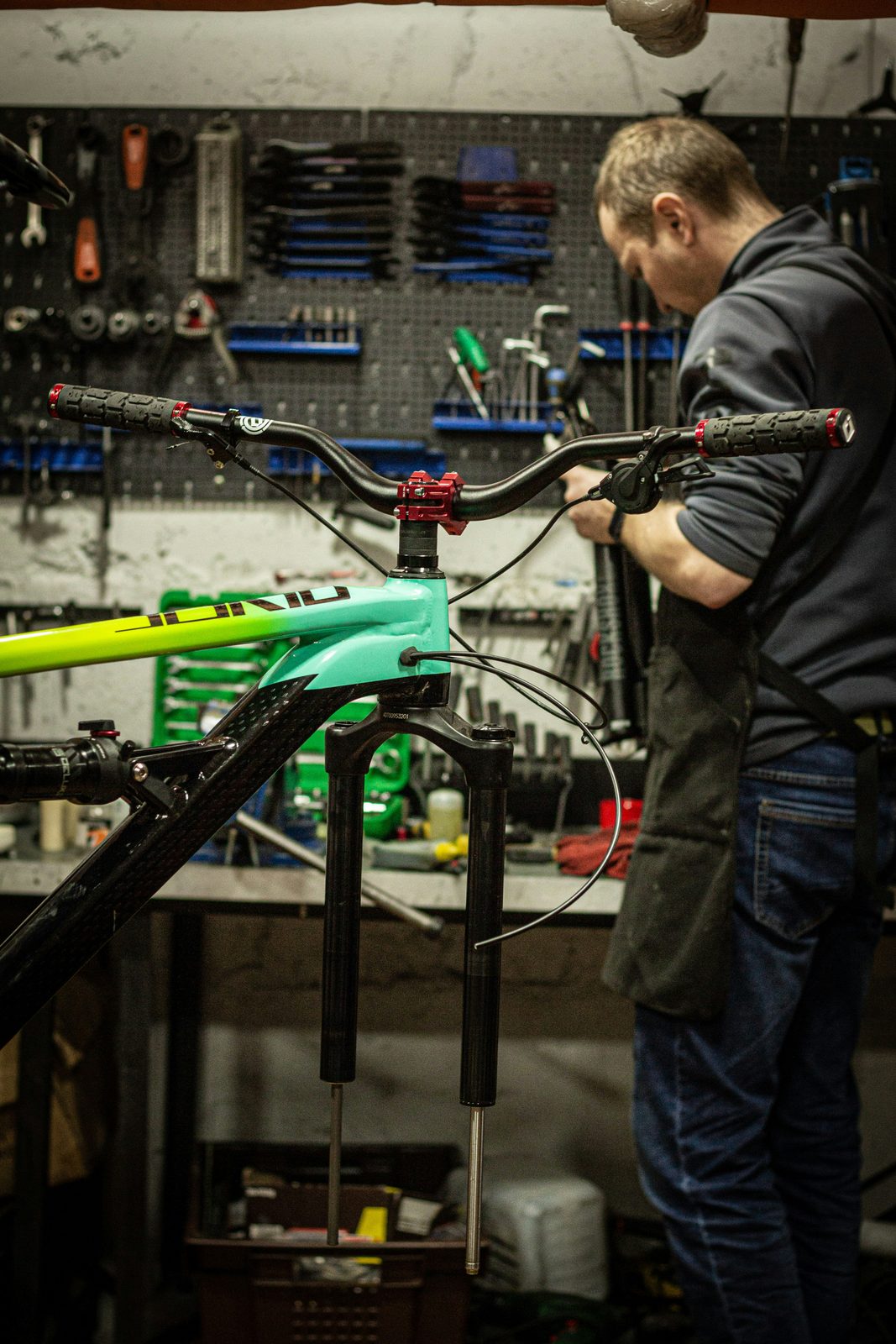 Bike mechanic working at a shop with tools on pegboard